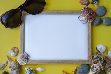 Fotokopi alanı, deniz kabukları, çakıl taşları, sarı arka plan için kompozisyon çerçevesi. Boşluk, üst görünüm, durgun hayat, düzlük. Deniz seyahati konsepti turizm ve tatil beldeleri. Yaz tatili