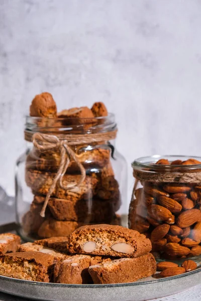 Traditional Italian cantuccini cookies with almonds in glass jar. Sweet dried biscuits. Homemade fresh Italian cookies cantuccini stacks and organic almond seeds. Healthy organic eating nutrition