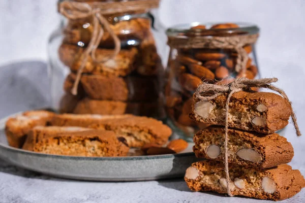 Traditional Italian cantuccini cookies with almonds in glass jar. Sweet dried biscuits. Homemade fresh Italian cookies cantuccini stacks and organic almond seeds. Healthy organic eating nutrition