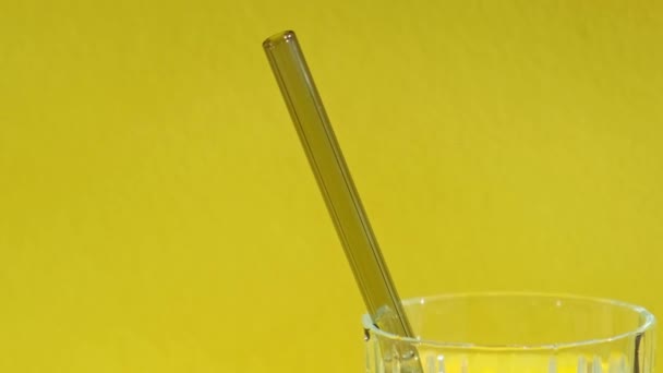 黄色の背景に水でガラスに再利用可能なガラスストロークリーニングブラシで設定します 廃棄物ゼロ プラスチックフリーコンセプト 持続可能なライフスタイル 廃棄物のない生活低廃棄物 — ストック動画