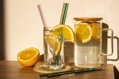 Glass of water with fresh lemon juice with Reusable glass Straws Detox cold tonic water with sunny lemon slices Low-waste lifestyle Eco-Friendly Drinking Straw Set with cleaning brush. Zero waste