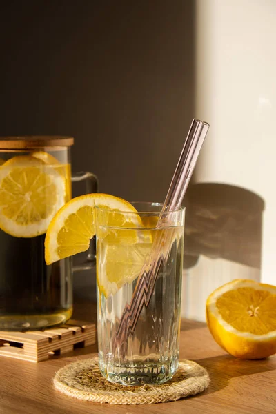 Glass of water with fresh lemon juice with Reusable glass Straws Detox cold tonic water with sunny lemon slices Low-waste lifestyle Eco-Friendly Drinking Straw Set with cleaning brush. Zero waste