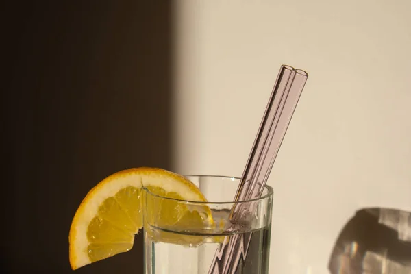 Glass of water with fresh lemon juice with Reusable glass Straws Detox cold tonic water with sunny lemon slices Low-waste lifestyle Eco-Friendly Drinking Straw Set with cleaning brush. Zero waste