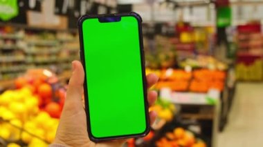 4k cep telefonu Chroma anahtarı. Alışveriş merkezinde elinde yeşil ekran olan akıllı telefonları olan kadınların yakın çekimleri. Süpermarketten yiyecek almak, marketi internetten almak. Alışveriş merkezi. Özellikler