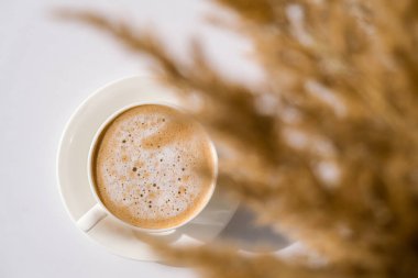 Pampa otları ve kahve ile beyaz bardak. Sabah kahvaltısında Cappuccino içmek. Düz yatıyordu. Duvar kağıdı. Estetik. Konforlu ev