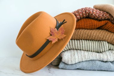 Sonbahar akçaağaç yaprağı ve bej renkli şık şapkalı sıcak örülmüş kazak yığını. Eski moda süveterler. Turuncu ve mavi renkler. Konforlu hygge konsepti Boşluğu kopyala Sonbahar sezonu