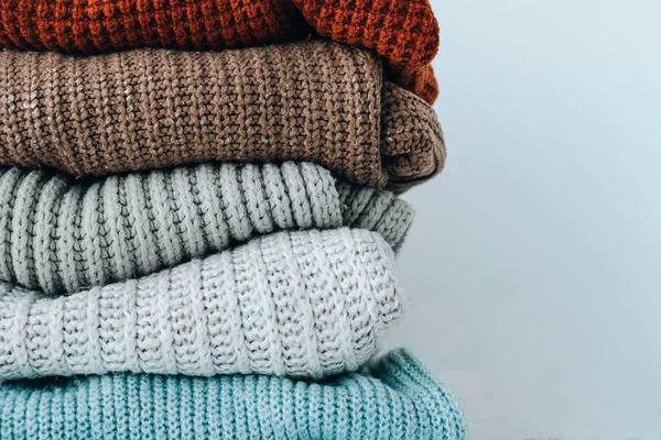 Stack of cozy knitted warm sweater. Sweaters in retro Style. Orange and blue colors. Cozy hygge concept Copy space Autumn winter season