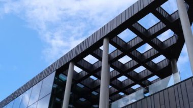 Gökyüzü arka planında cam cepheli modern ofis binası. Ofis binasının cam duvarında bulutların yansıması var. Modern Avrupa binasının dış cephesi