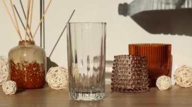 Masaya boş bardağa su ekliyorum. Güneşli bir gün. Su cama dökülüyor. Arka planda ev dekorasyonları Günlük rutin su dengesi