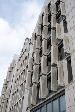 Gökyüzü arka planında cam cepheli modern ofis binası. Ofis binasının cam duvarında bulutların yansıması var. Modern Avrupa binasının dış cephesi