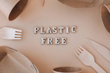 Çevre dostu, tek kullanımlık, geri dönüşümlü, gübrelenebilir sofra takımı etrafında plastiksiz metin. Kağıt yiyecek kutuları, tarafsız bej arka planda tabaklar. Sürdürülebilir yaşam tarzı konsepti. Düz Yeryüzü tonları