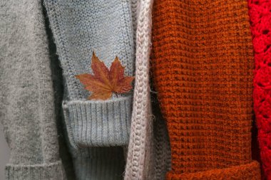 Sonbahar akçaağaç yaprağıyla örülmüş sıcak süveter yığını. Eski moda süveterler. Turuncu ve mavi renkler. Konforlu hygge konsepti Boşluğu kopyala Sonbahar sezonu