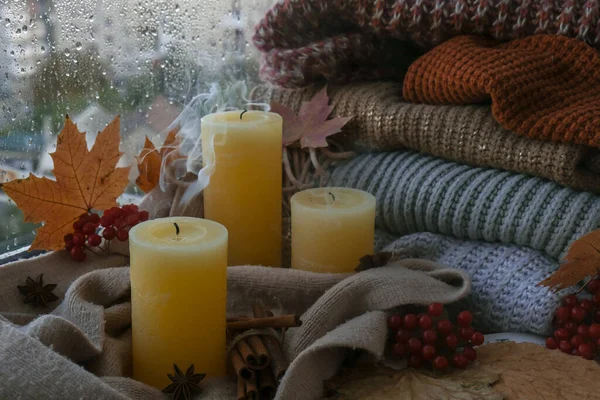 Blown candle with smoke Hello Fall, celebrating autumn holidays at cozy home on the windowsill Hygge atmosphere Thanksgiving leaves, spices and candle on cozy knitted sweater in warm yellow lights. Selective focus Raining Outside the window