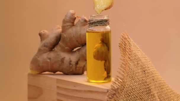 玻璃瓶中的生姜精油滴滴 生姜根在米色背景上 健康的替代生活 护发的天然化妆品成分 — 图库视频影像