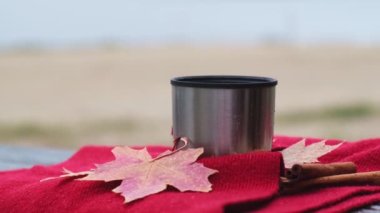 Sonbahar parkında termo bardaktan sıcak çay dökülüyor. Kırmızı eşarp sonbahar piknik termosu. Sonbahar konsepti