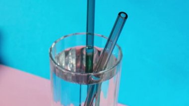 Mavi arka planda suyla birlikte yeniden kullanılabilir cam kamışları, temizlik fırçasıyla birlikte çevre dostu içecek saman setine koyun. Sıfır atık, plastiksiz konsept. Sürdürülebilir yaşam tarzı. Serbest yaşam israfı Düşük