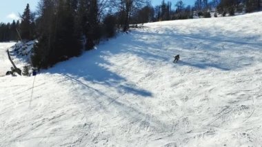 Kışın dağlarda kayak yapan kayakçı. Kayak alanının yukarıdan görünüşü. Tepeden kayakçılar ve snowboardcular iniyor. Karpatlar 'ın dağlık kayak merkezinde kayakçılar ve asansörler, görkemli karlı kış.