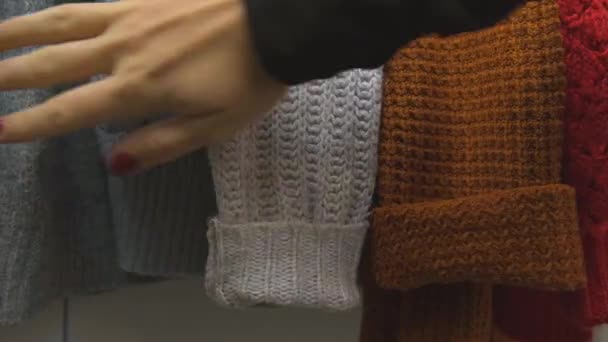 暖かいセーター 女性の手の動きの服は慈善団体に寄付を着用するものを選択します 女性の手は 衣料品店で服を選択する危険性を略奪した ショッピングモールで服を購入 販売促進秋 — ストック動画