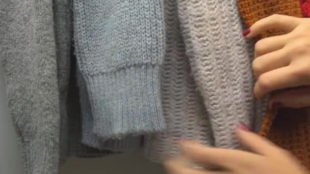 暖かいセーター 女性の手の動きの服は慈善団体に寄付を着用するものを選択します 女性の手は 衣料品店で服を選択する危険性を略奪した ショッピングモールで服を購入 販売促進秋 — ストック動画