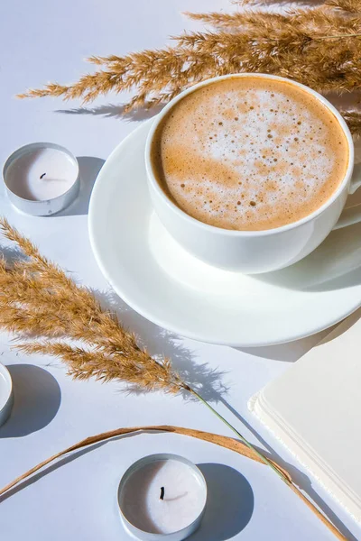 Pampas grass and white cup with coffee. Empty notebook making a plan for the day. Drinking Cappuccino in the breakfast morning at home. Flat lay. Wallpaper. Aesthetics Cozy home