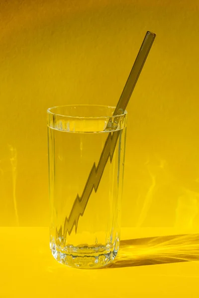 Reusable glass Straws in Glass with water on yellow background Eco-Friendly Drinking Straw Set with cleaning brush. Zero waste, plastic free concept. Sustainable lifestyle. Waste free living Low waste