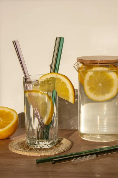 Glass of water with fresh lemon juice with Reusable glass Straws Detox cold tonic water with sunny lemon slices Low-waste lifestyle Eco-Friendly Drinking Straw Set with cleaning brush. Zero waste