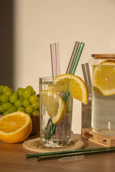 Glass of water with fresh lemon juice with Reusable glass Straws Detox cold tonic water with sunny lemon slices Low-waste lifestyle Eco-Friendly Drinking Straw Set with cleaning brush. Zero waste