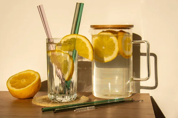 Glass of water with fresh lemon juice with Reusable glass Straws Detox cold tonic water with sunny lemon slices Low-waste lifestyle Eco-Friendly Drinking Straw Set with cleaning brush. Zero waste
