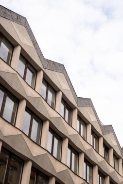 Gökyüzü arka planında cam cepheli modern ofis binası. Ofis binasının cam duvarında bulutların yansıması var. Modern Avrupa binasının dış cephesi