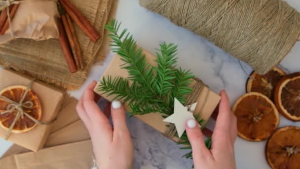 女人用新年礼物做盒子 用手工纸包好 再用冷杉枝条装饰 假期和礼物的概念 手工制造环保环保环保环保圣诞礼物零浪费 — 图库视频影像