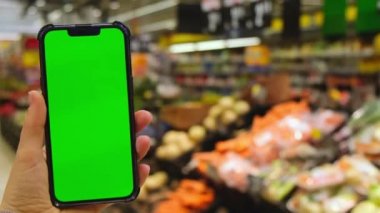 4k cep telefonu Chroma anahtarı. Alışveriş merkezinde elinde yeşil ekran olan akıllı telefonları olan kadınların yakın çekimleri. Süpermarketten yiyecek almak, marketi internetten almak. Alışveriş merkezi. Özellikler