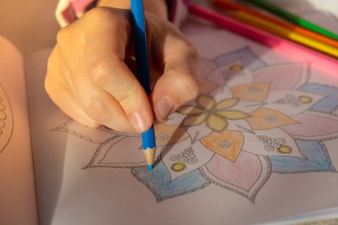Woman coloring antistress page. Female hand painting mandala. Female painting mandalas to combat stress. Relaxing hobby mental wellbeing and art therapy. Woman paints sketch, meditative process of