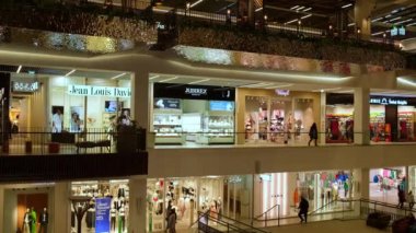 Gdansk Polonya - Nisan 2022. Forum galerisi alışveriş merkezi gece binanın içini gösteriyor. İnsanlar ünlü popüler dükkanlardan alışveriş merkezine doğru yürüyorlar. Modern alışveriş ve eğlence