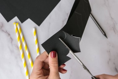 Kağıt sopalarla şeritli pipetler. Cadılar Bayramı süslemeleri. Düzlük, üst görünüm Mutlu Cadılar Bayramı partisi konsepti. Çocuk sanat projesi. Diy konsepti. Adım adım Zanaat