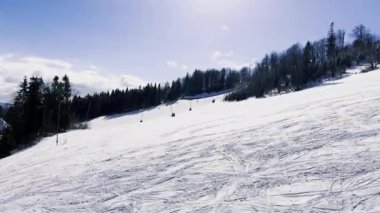 Kışın dağlarda kayak yapan kayakçı. Kayak alanının yukarıdan görünüşü. Tepeden kayakçılar ve snowboardcular iniyor. Karpatlar 'ın dağlık kayak merkezinde kayakçılar ve asansörler, görkemli karlı kış.