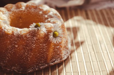 Kek papatya çiçeğiyle süslenmiş, kır tarzında. Otantik fotoğraf. Paskalya konsepti tebrik kartı geçmişi. Güneş ışınları ev yapımı fırın konsepti. Yaz, bahar zamanı tarifi. Anneler Günü, Doğum Günü