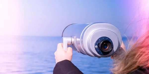 Tourist looking through coin operated binoculars. Binocular telescope on the observation deck for tourism. Sea background. Binoculars watching at horizon at ship deck. Discover new places Travel