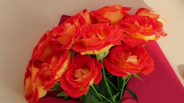 Bej arka planda kağıt zarfla süslenmiş bir buket kırmızı gül. Tatil için çiçek hediyesi. Teklif ya da düğün hediyesi fikri. Bayram için selamlar Yavaş çekim