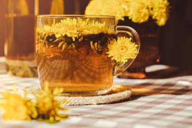 Dandelion flower healthy tea in glass cup on table. Herbal medicine Delicious tisane tea from with fresh yellow blossom dandelion flowers inside tea cup. Green clearing infusion Wildflowers Eco