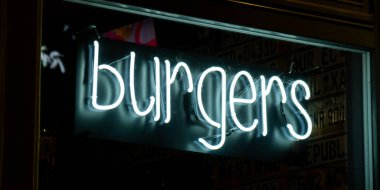 Burgers inscription in neon lights at night. Electric sign at night nightlife concept. Modern fluorescent life style luminescent. LED light sign text color lighting