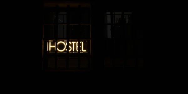 Hostel inscription in neon lights at night. Electric sign at night nightlife concept. Modern fluorescent life style luminescent. LED light sign text color lighting