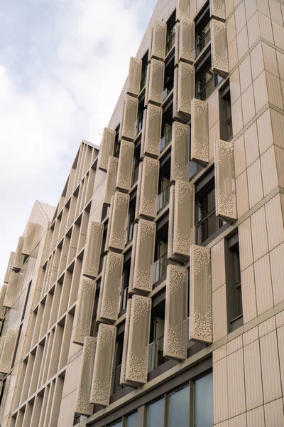 Gökyüzü arka planında cam cepheli modern ofis binası. Ofis binasının cam duvarında bulutların yansıması var. Modern Avrupa binasının dış cephesi