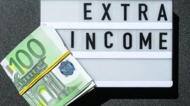 4k zoom in out Lightbox board with word EXTRA INCOME in black letters around euro banknotes. Money, Business, finance, investment, saving. Cash bill. Business budget of wealth and prosperity finance