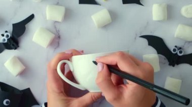 Beyaz bardağa kadın eli boyası korkunç valeler çocuklar için cadılar bayramı aktiviteleri bayram sanat çocukları el yapımı süslemeler yapıyor. Sanat dersi için ev içi fikirlere sosyal açıdan mesafeli