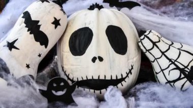 4k zoom in out Halloween background with painted face pumpkins and autumn leaves. Diy. Do it yourself. Halloween decorations, black and white pumpkins, bats, ghosts. Halloween party greeting card