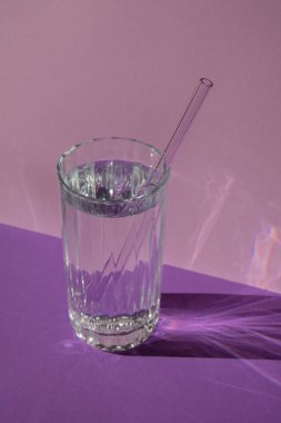 Mor menekşe arka planda suyu olan yeniden kullanılabilir cam pipetler temizlik fırçasıyla birlikte çevre dostu saman içme seti. Sıfır atık, plastiksiz konsept. Sürdürülebilir yaşam tarzı. Serbest yaşam israfı