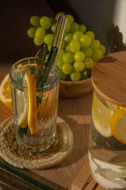 Bir bardak taze limon suyu ve yeniden kullanılabilir cam kamış detoks soğuk tonik su ve güneşli limon dilimleri düşük atık yaşam tarzı Eko-Dost Canlısı Seti temizlik fırçası ile birlikte. Sıfır atık