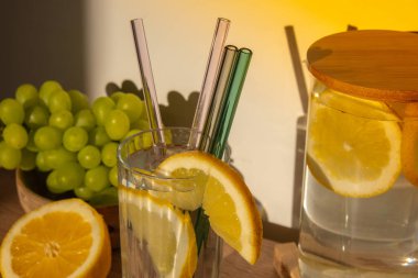 Bir bardak taze limon suyu ve yeniden kullanılabilir cam kamış detoks soğuk tonik su ve güneşli limon dilimleri düşük atık yaşam tarzı Eko-Dost Canlısı Seti temizlik fırçası ile birlikte. Sıfır atık