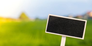 Blank Black billboard against green field landscape Empty mockup template Blackboard label at farm land. Copy space banner for your text. Agricultural landscape Summer landscape with hilly field
