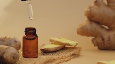 Esaslı zencefil yağı damlayan cam pipet, bej arka planda zencefil kökü. Sağlıklı alternatif yaşam. Zingiber officinale Earth ses tonları Aromaterapi, spa ve bitkisel ilaç malzemeleri. & Aç